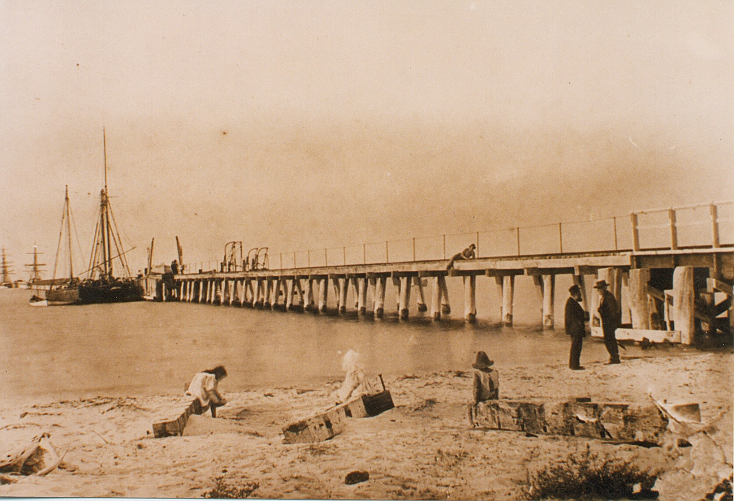 Earliest known photo of the Jetty showing a singular sail ship and children playing on the beach - Jetty History.