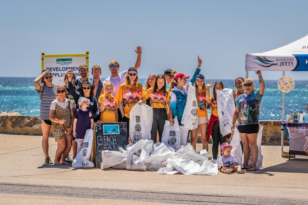 Large group of people posing for a photo with their rubbish bags post Beach Cleanup, including Jetty Crew, Staff, Volunteers and members of Public.