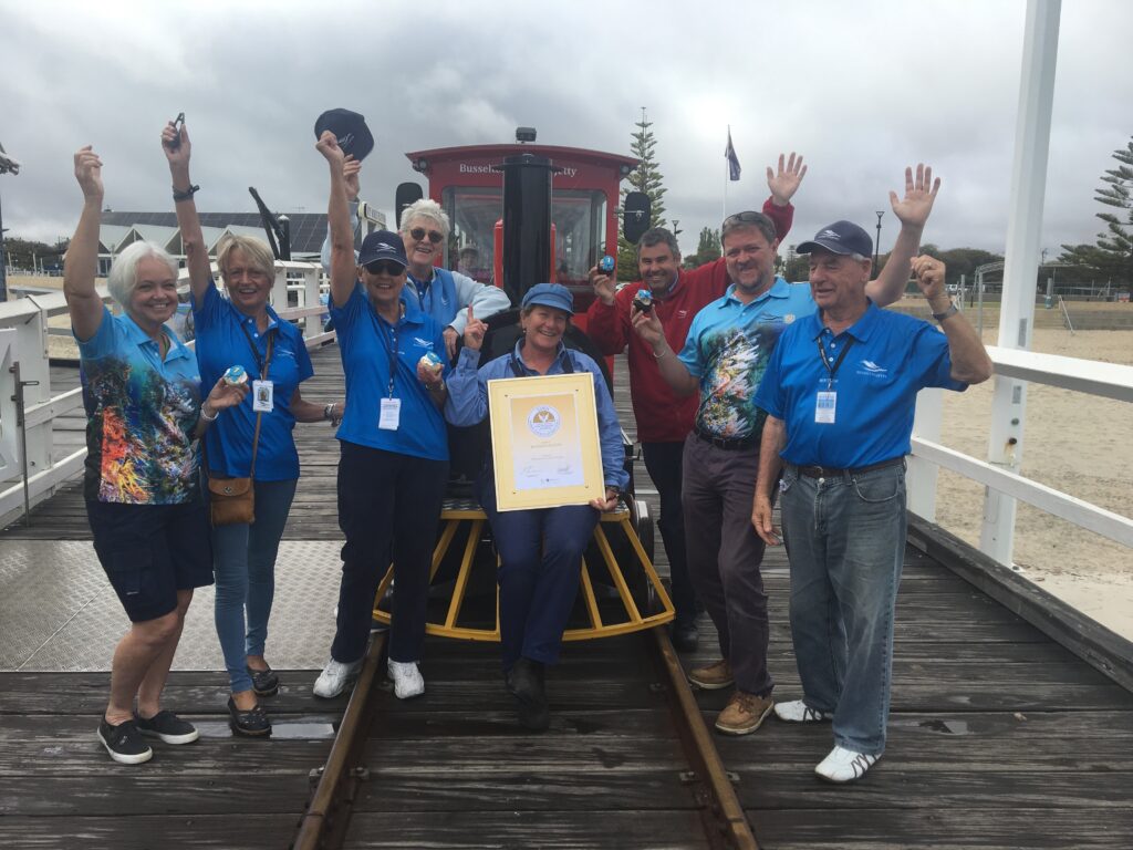Busselton Jetty Staff and Volunteers posing happily with a Tourism Award in-front of the Jetty Train.
