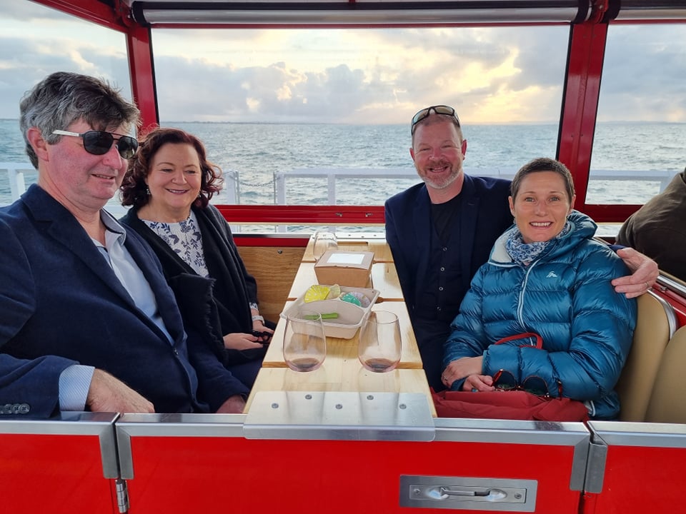 Four event goers on the Jetty Train with our wine/cheese board placed across their laps, wine in hand and ready to party.